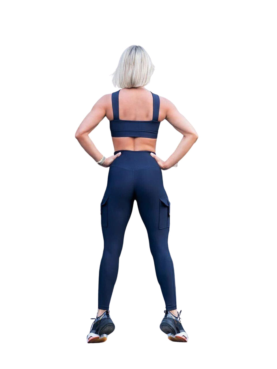 Eine Person mit kurzen Haaren steht mit den Händen auf den Hüften in Lisminas 1141 Leggings mit Taschen in Marineblau und betont die hohe Taille.